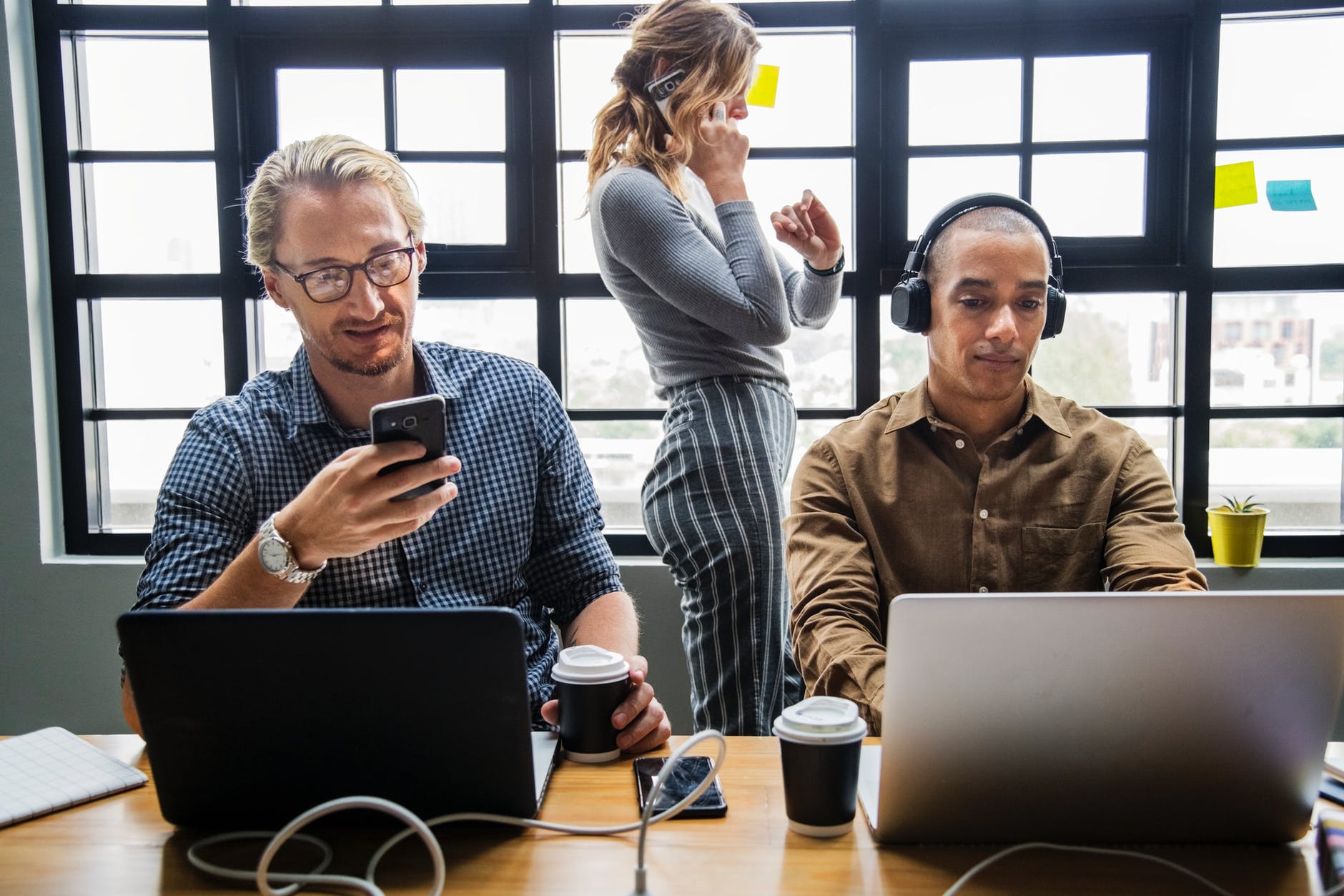 standing woman beside two men in front of laptop computer