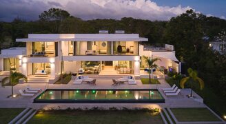 a contemporary house in Barbados with lots of glass shown at night