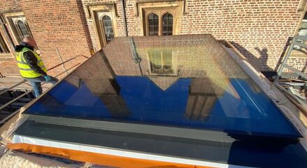 oversized venting rooflight on a roof with a man in a high vis stood to the left of it