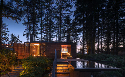 Rural woodland retreat with frameless glass walls and sliding doors