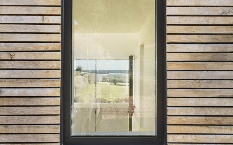 Aluminium minimal framed glass casement window set in timber wall