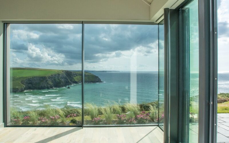 Combining natural materials with modern frameless floor to ceiling glass stitches a contemporary and luxurious cliffside home