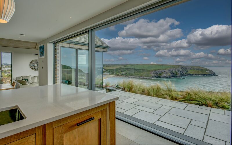 Ultra slim framed floor to ceiling sliding glass doors connects the cliffside home to the Cornish coastal surroundings.