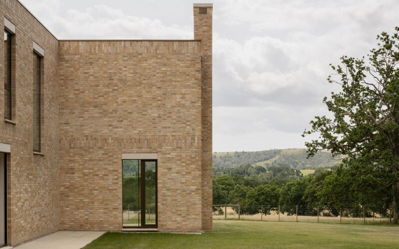 frameless window within the brick wall of a bespoke house set in the countryside