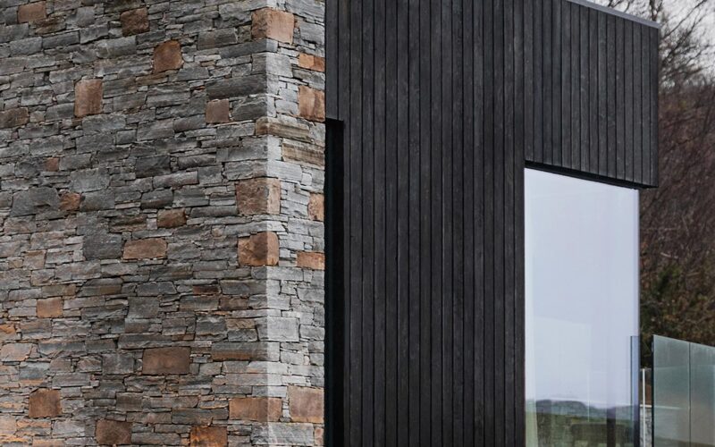 a frameless window in black timber cladding