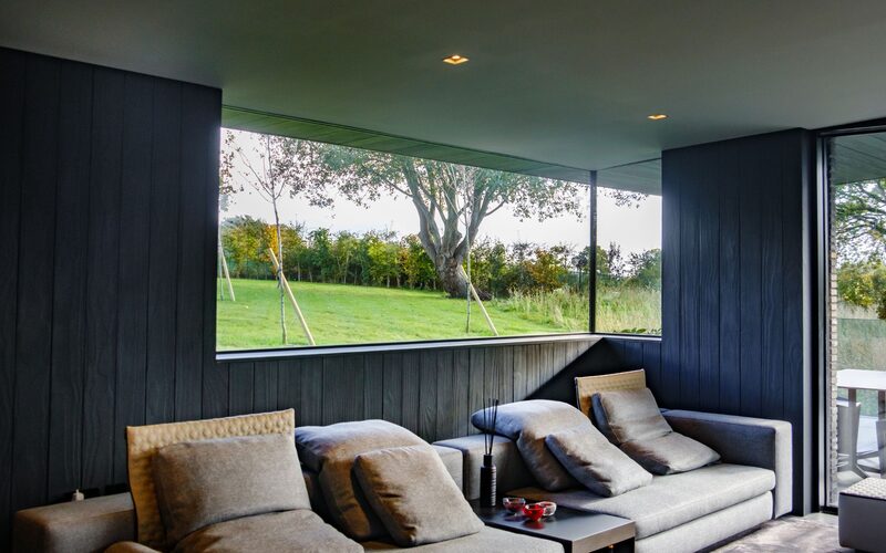 a frameless corner window to a living room with dark walls