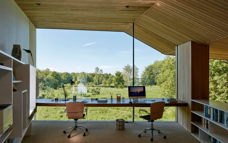 a frameless window creating a full glass wall to a home office overlooking the trees