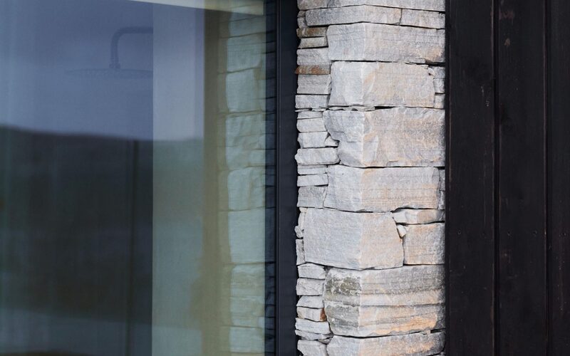 a close up image of a frameless window fit into a stone wall