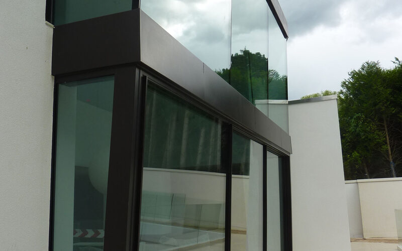 Sliding glass patio doors below fixed frameless glass facade