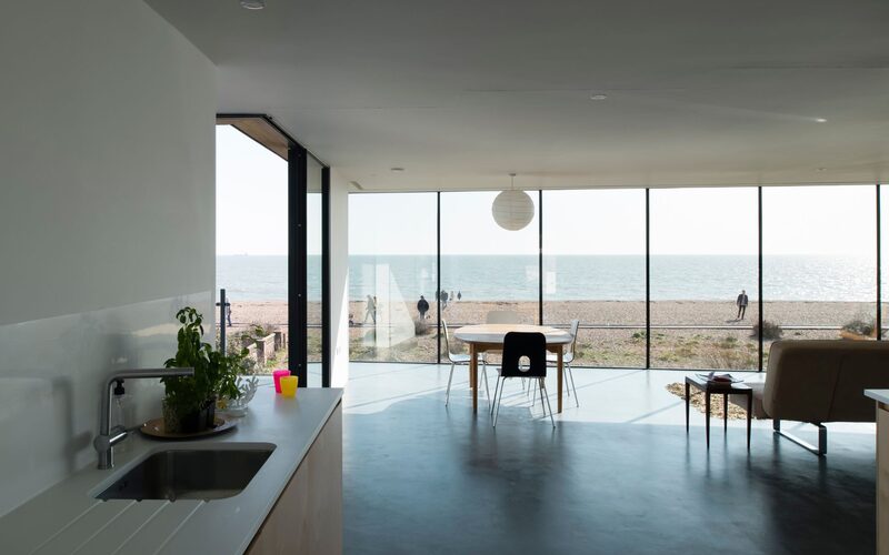 looking out through a glass wall over a beach on old fort road