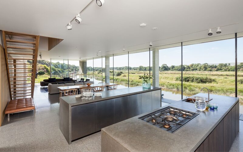 Glass wall living room facade to modern riverside dwelling.