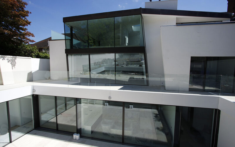 Multiple minimal sliding glass doors to basement extension with structural glass balustrades