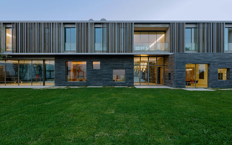 Slim framed architectural glazing and sliding doors create extensive glazed facade to modern home