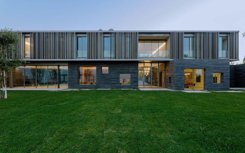 Slim framed architectural glazing and sliding doors create extensive glazed facade to modern home