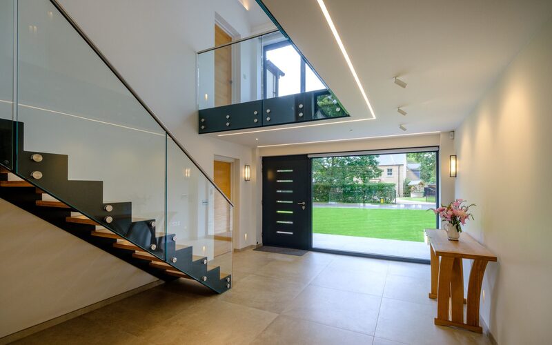 Oversized wide glass to entrance of modern house in Cambridgeshire allows natural light to flood in.