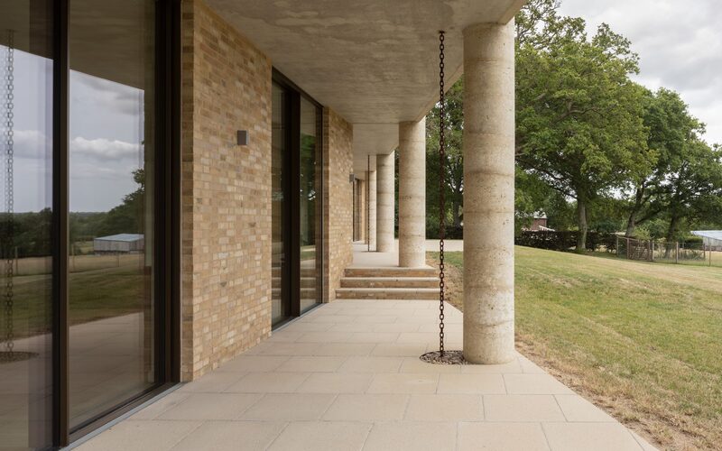 exterior view of luxury patio doors within a light brick wall overlooking a field