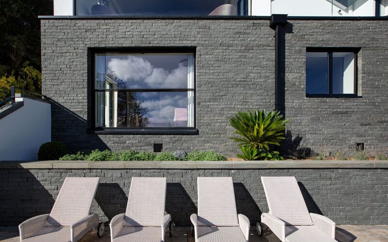 an external view of a modern sash window set into a grey brick wall