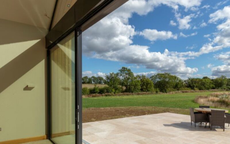 double height glass wall with sliding glass doors to farmhouse in leicester