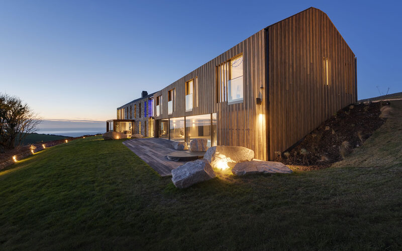 Stone and timber clad new build coastal home with minimal frameless glazing