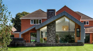 modern extension to a traditional red brick house with a structural glass wall